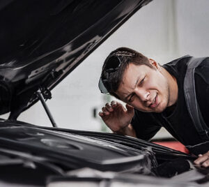 Hombre revisando el motor de su carro GNV al detectar ruidos extraños, señal de que necesita mantenimiento.