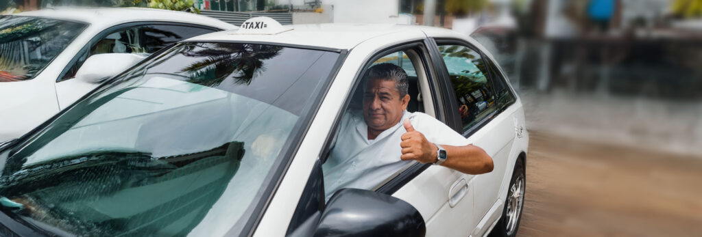 alt="Taxista en su vehículo blanco mostrando pulgar arriba. Crédito justo y accesible con tarifas claras en Credimovil."